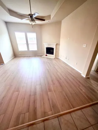 an empty room with wooden floor fireplace and windows