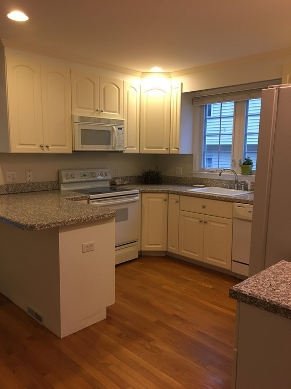 120 Maple Street, Unit 120 Needham, MA 02492 - Photo 7 of 14 a kitchen with stainless steel appliances granite countertop wooden cabinets a sink and dishwasher a stove with wooden floor