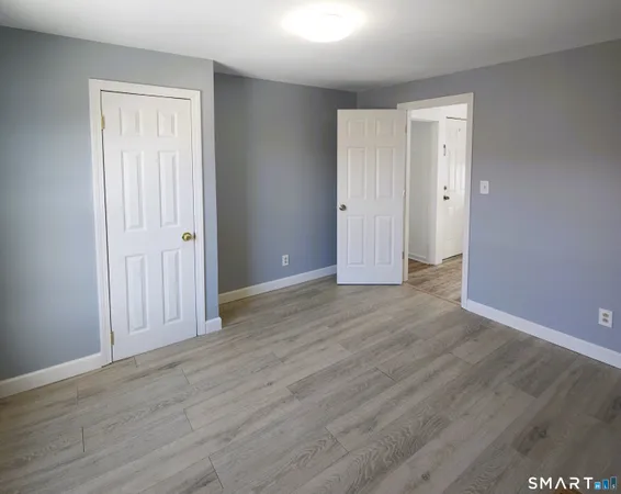 an empty room with wooden floor & closet area