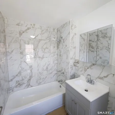 a bathroom with a bathtub sink and mirror