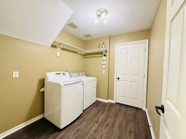 a utility room with wooden floor washer and dryer