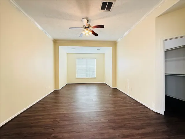 an empty room with wooden floor chandelier fan and windows