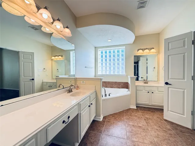 a spacious bathroom with a tub a double vanity sink a window and a mirror