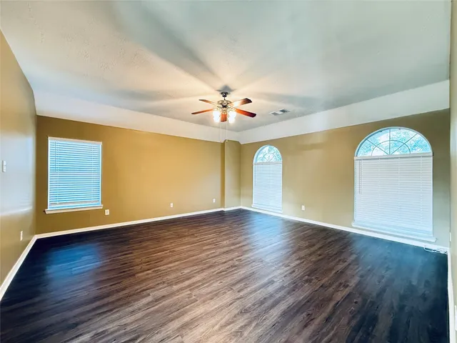 an empty room with wooden floor and windows