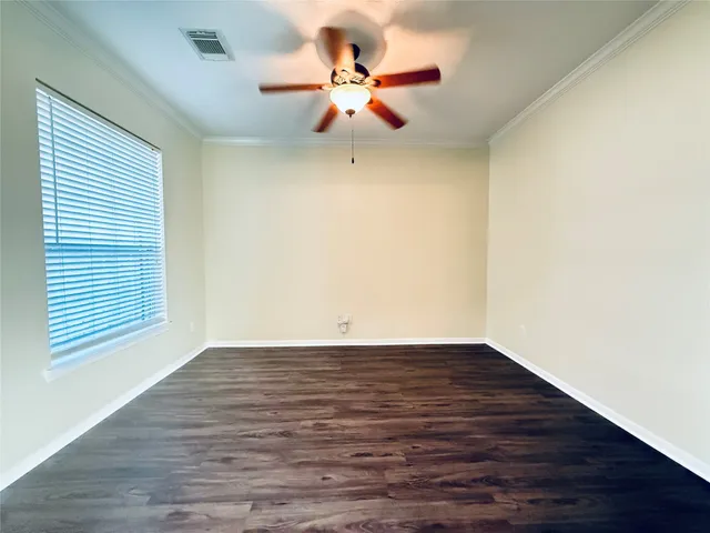 a view of an empty room with wooden floor and a ceiling fan
