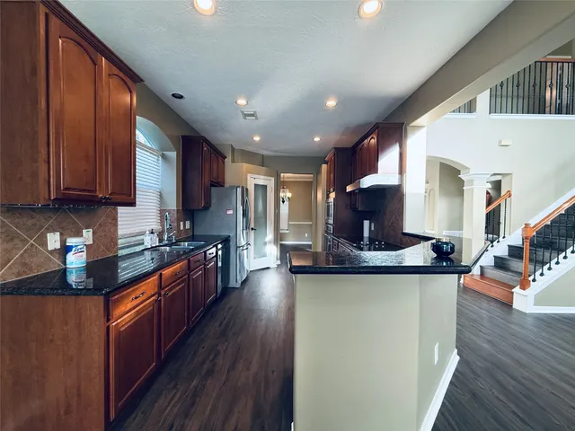 a kitchen with stainless steel appliances granite countertop wooden cabinets a stove top oven a sink and dishwasher