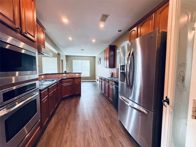 a kitchen with stainless steel appliances a refrigerator a stove a sink and a microwave