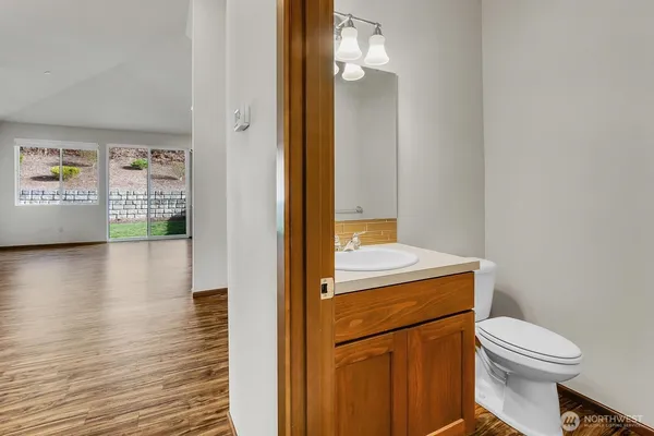 a bathroom with a toilet a sink and wooden floor