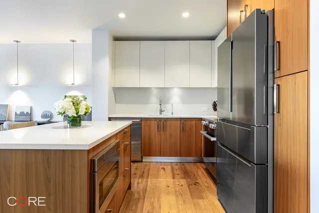 a living room with couches chairs and kitchen view with wooden floor