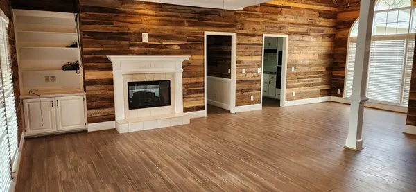 an empty room with wooden floor fireplace and windows