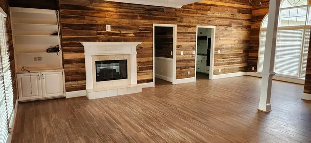 an empty room with wooden floor fireplace and windows