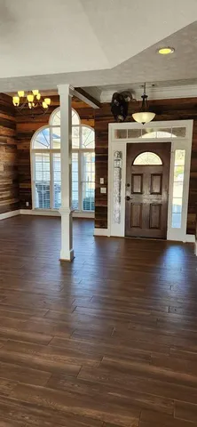 an empty room with wooden floor fireplace and windows
