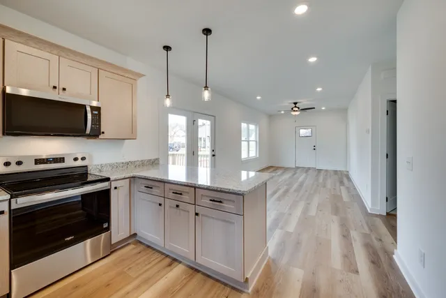 a open kitchen with white cabinets stainless steel appliances and wooden floor