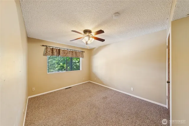 an empty room with windows and ceiling fan