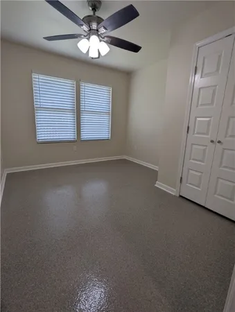 an empty room with windows and fan