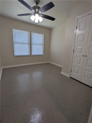 an empty room with windows and fan