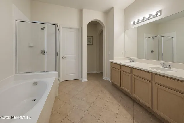 a spacious bathroom with a double vanity sink a large mirror and a bathtub