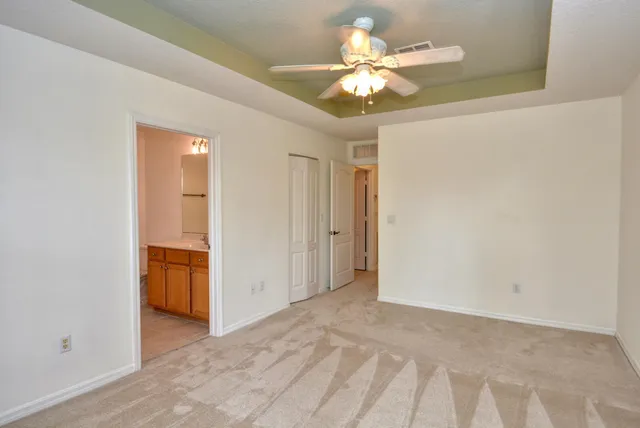 an empty room with a chandelier fan and a bathroom
