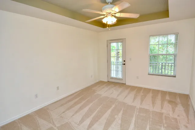 an empty room with windows and fan