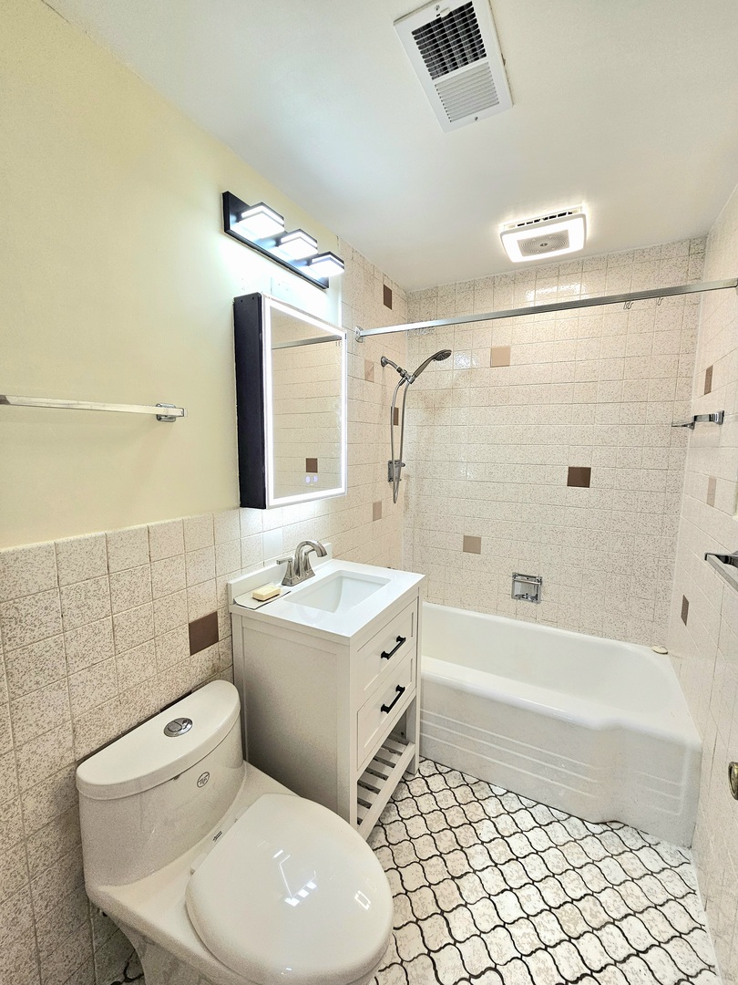 7434 Emerson Street Morton Grove, IL 60053 - Photo 30 of 43 a bathroom with a toilet a sink a mirror and bathtub