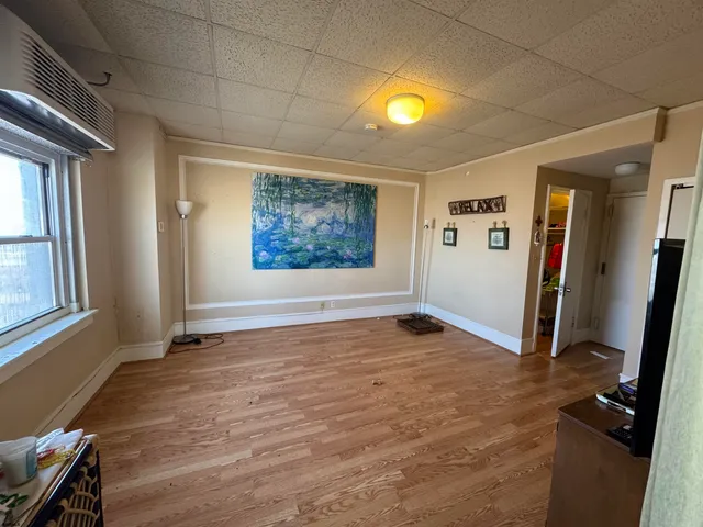 a view of an empty room with window and wooden floor