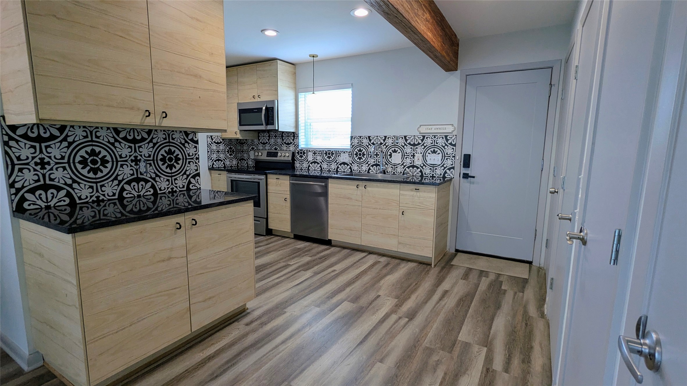 4505 Teri Road, Unit A Austin, TX 78744 - Photo 4 of 23 A striking kitchen with elegant wooden cabinets, dark countertops, and a decorative tile backsplash.