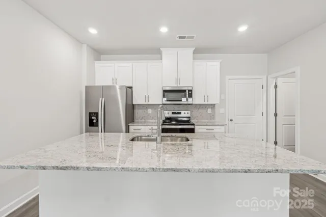 a kitchen with stainless steel appliances granite countertop a sink a stove and a refrigerator