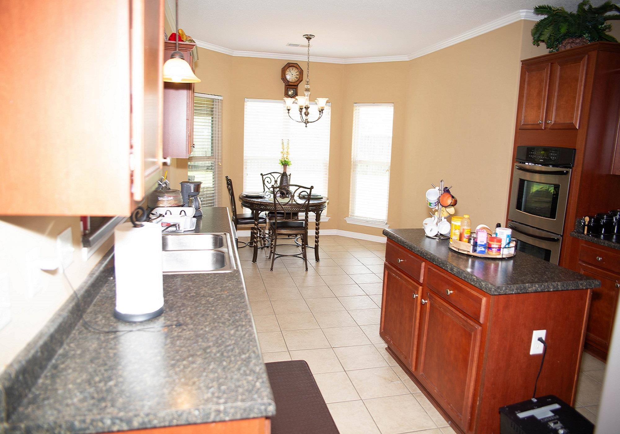 8483 Boothes Ridge Drive Memphis, TN 38125 - Photo 12 of 38 Kitchen with double oven, light tile patterned flooring, a chandelier, and dark countertops