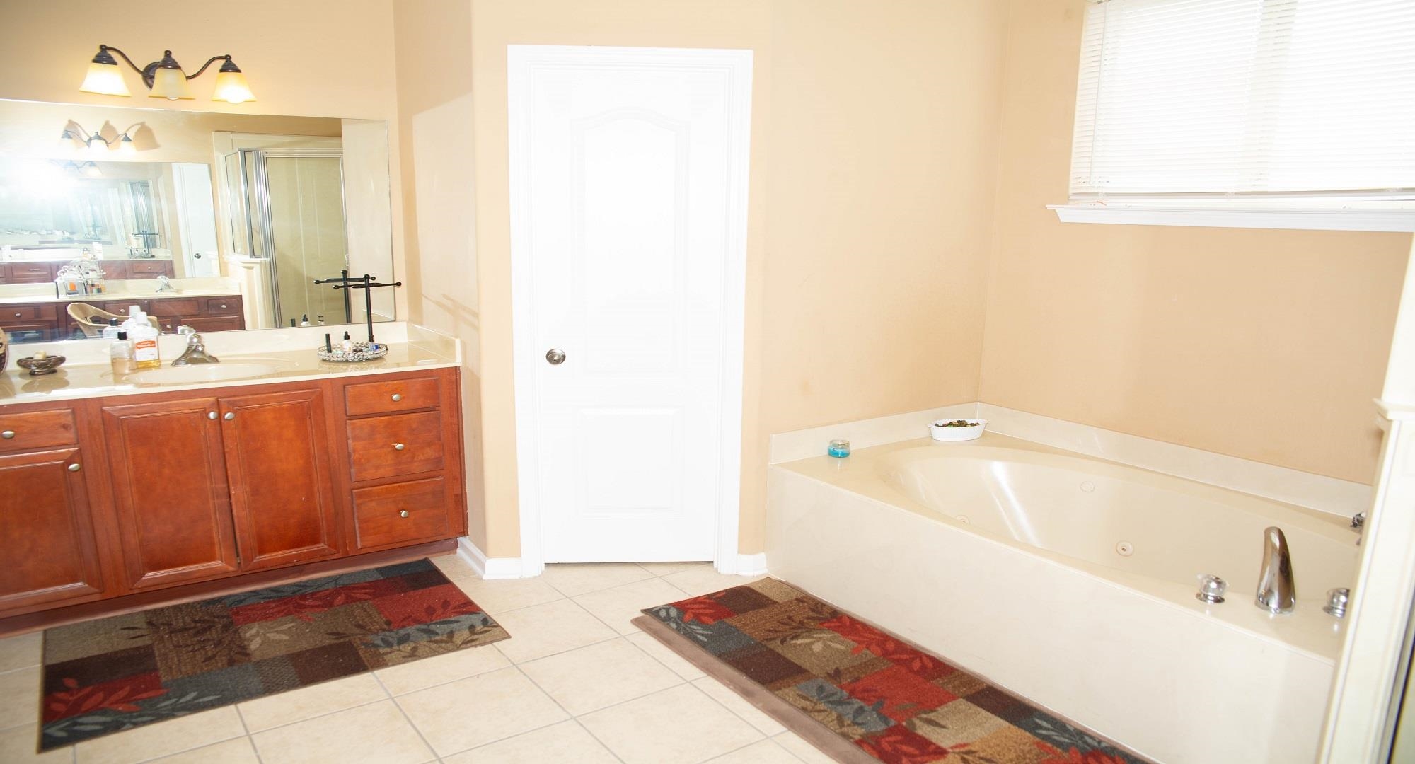 8483 Boothes Ridge Drive Memphis, TN 38125 - Photo 21 of 38 Full bathroom with tile patterned flooring, a shower stall, a garden tub, and vanity