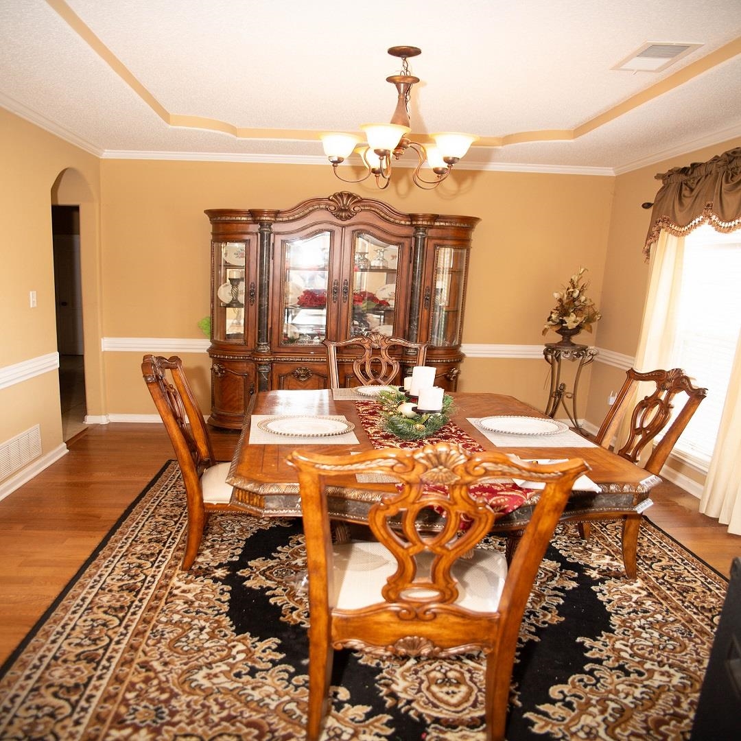 8483 Boothes Ridge Drive Memphis, TN 38125 - Photo 28 of 38 Dining room with visible vents, arched walkways, wood finished floors, a raised ceiling, and a chandelier