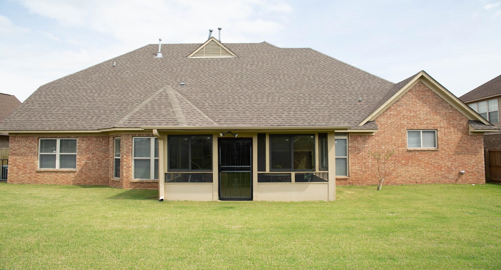 8483 Boothes Ridge Drive Memphis, TN 38125 - Photo 36 of 38 Rear view of property featuring roof with shingles, a sunroom, brick siding, fence, and a yard
