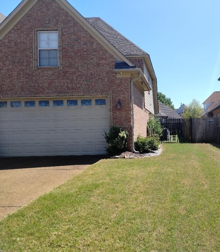 8483 Boothes Ridge Drive Memphis, TN 38125 - Photo 6 of 38 View of home's exterior with a yard, brick siding, driveway, and fence