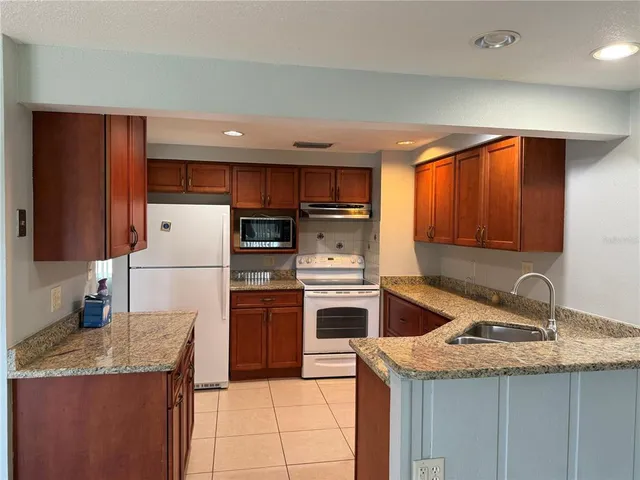 a kitchen with granite countertop kitchen island stainless steel appliances a refrigerator sink and microwave