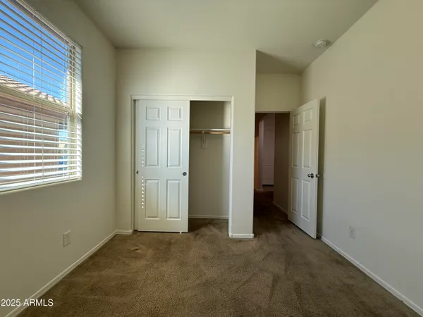 a view of an empty room with closet and a window