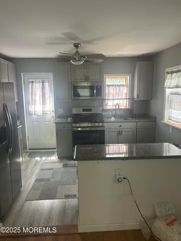 a kitchen with stainless steel appliances granite countertop a sink a stove a refrigerator a washer dryer and cabinets