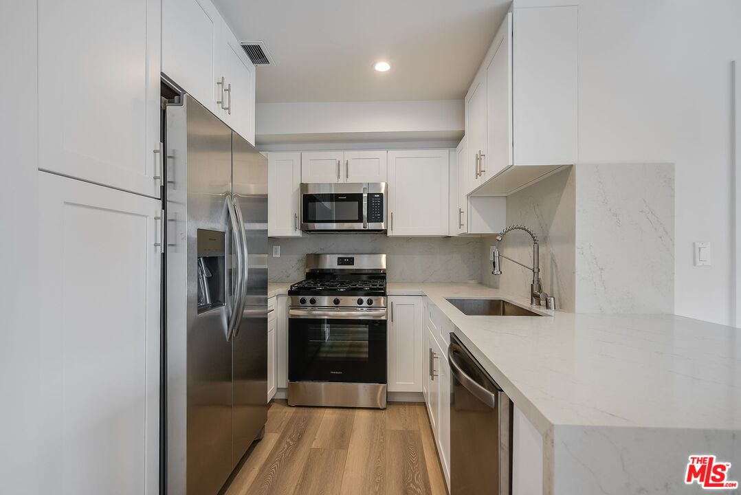 11675 Darlington Avenue, Unit 301 Los Angeles, CA 90049 - Photo 14 of 16 a kitchen with a sink a stove and refrigerator