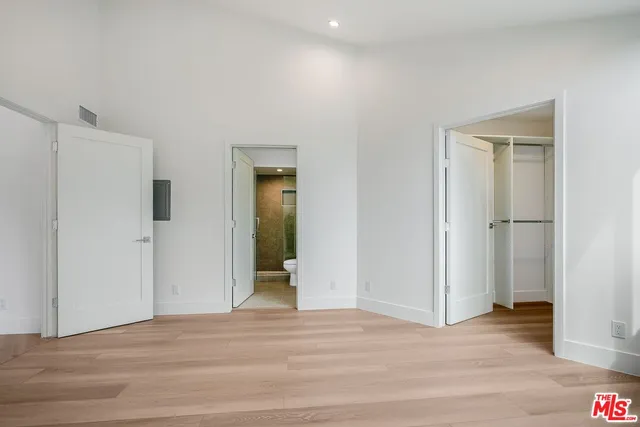a view of an empty room with wooden floor and closet