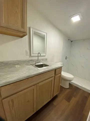 a bathroom with a granite countertop sink a toilet and a mirror
