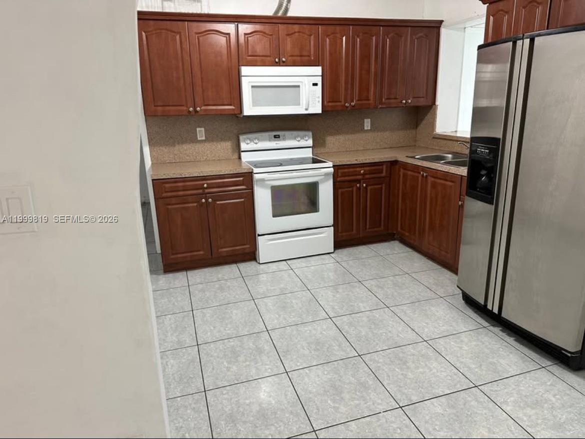9021 Southwest 30th Terrace Miami, FL 33165 - Photo 3 of 18 a kitchen with a stove a sink and a refrigerator