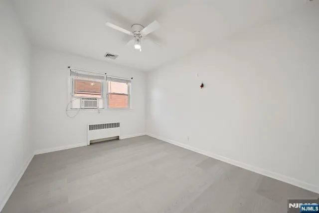 an empty room with windows and ceiling fan