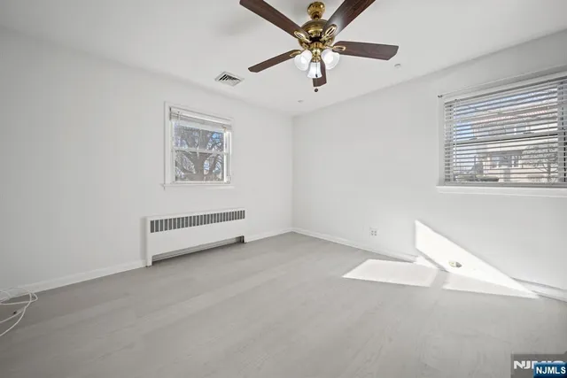 an empty room with windows and fan