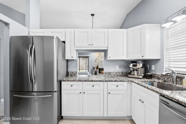 a kitchen with stainless steel appliances granite countertop a refrigerator a sink and white cabinets