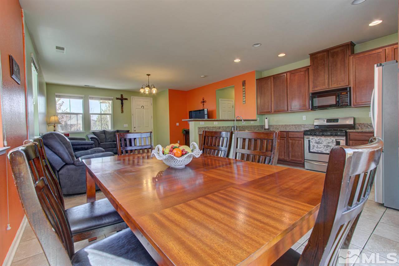 9045 Convair Way Reno, NV 89506 - Photo 11 of 34 a kitchen with stainless steel appliances granite countertop a stove top oven a sink a dining table and chairs with wooden floor