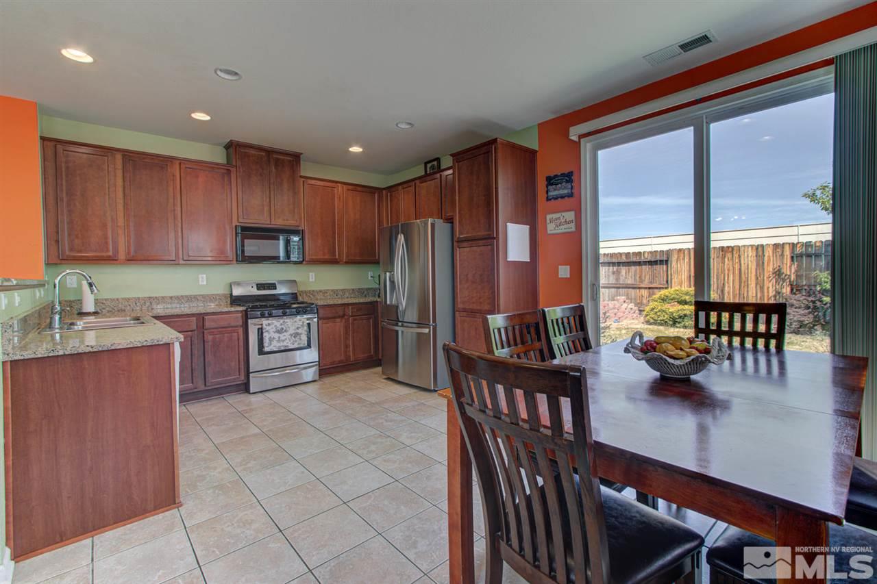 9045 Convair Way Reno, NV 89506 - Photo 8 of 34 a kitchen with stainless steel appliances granite countertop a stove a refrigerator a sink a dining table and chairs with wooden floor