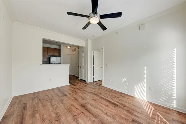 a view of empty room with wooden floor and ceiling fan