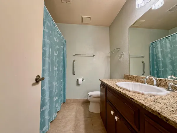 a bathroom with a granite countertop sink a toilet a mirror and shower