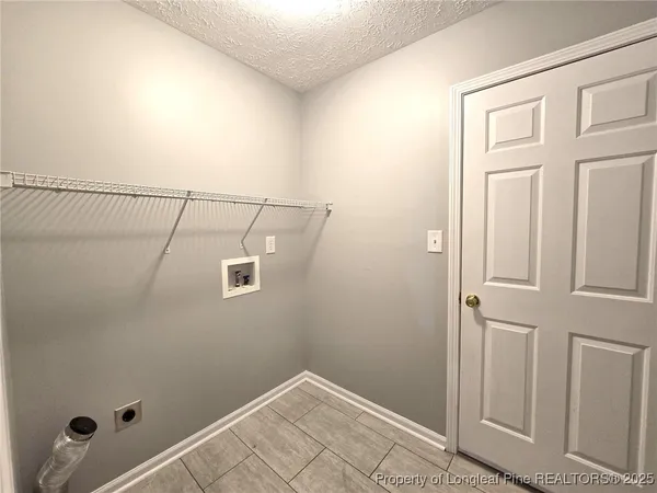 an empty room with a chandelier fan and windows