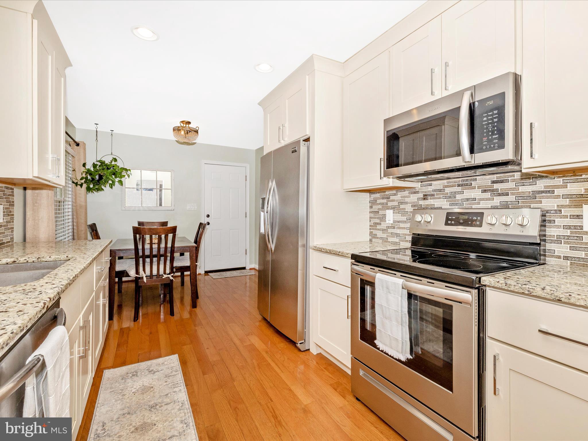 9204 Oak Tree Circle Frederick, MD 21701 - Photo 12 of 58 a kitchen with stainless steel appliances kitchen island granite countertop a stove a sink and a microwave