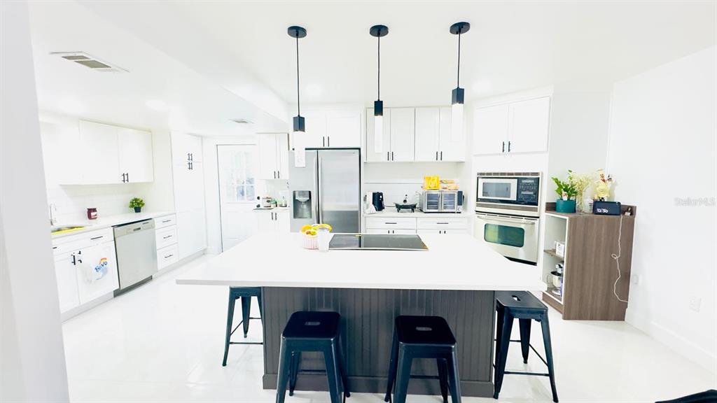 14614 Bayonne Road Orlando, FL 32832 - Photo 9 of 23 a kitchen with stainless steel appliances kitchen island wooden floor and white cabinets