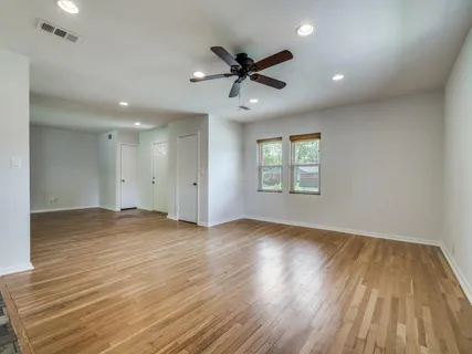 a view of empty room with wooden floor and fan